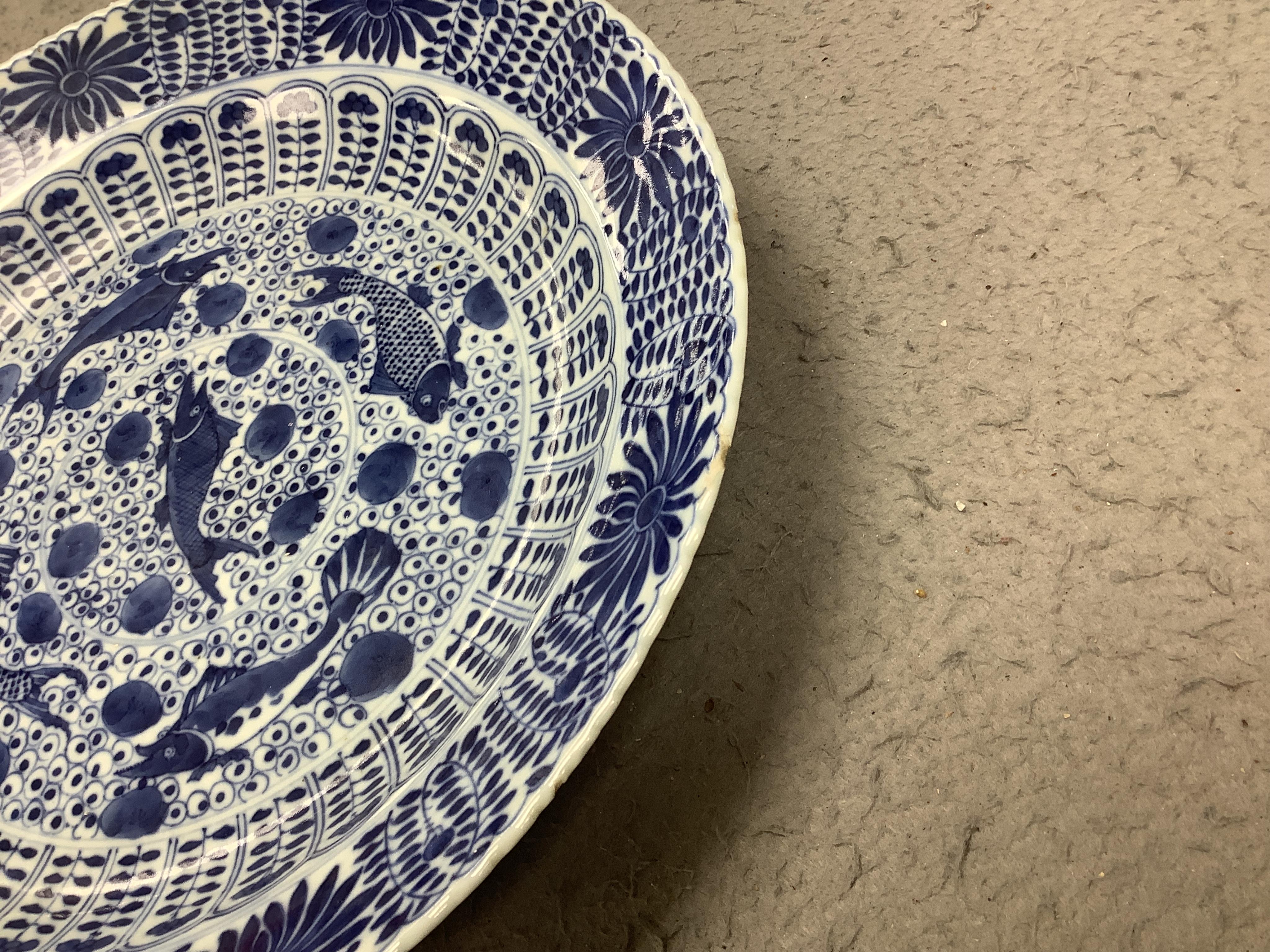 A Chinese blue and white 'fish' dish, Kangxi mark but c.1900, 33cm diameter. Condition - slight chipping to rim